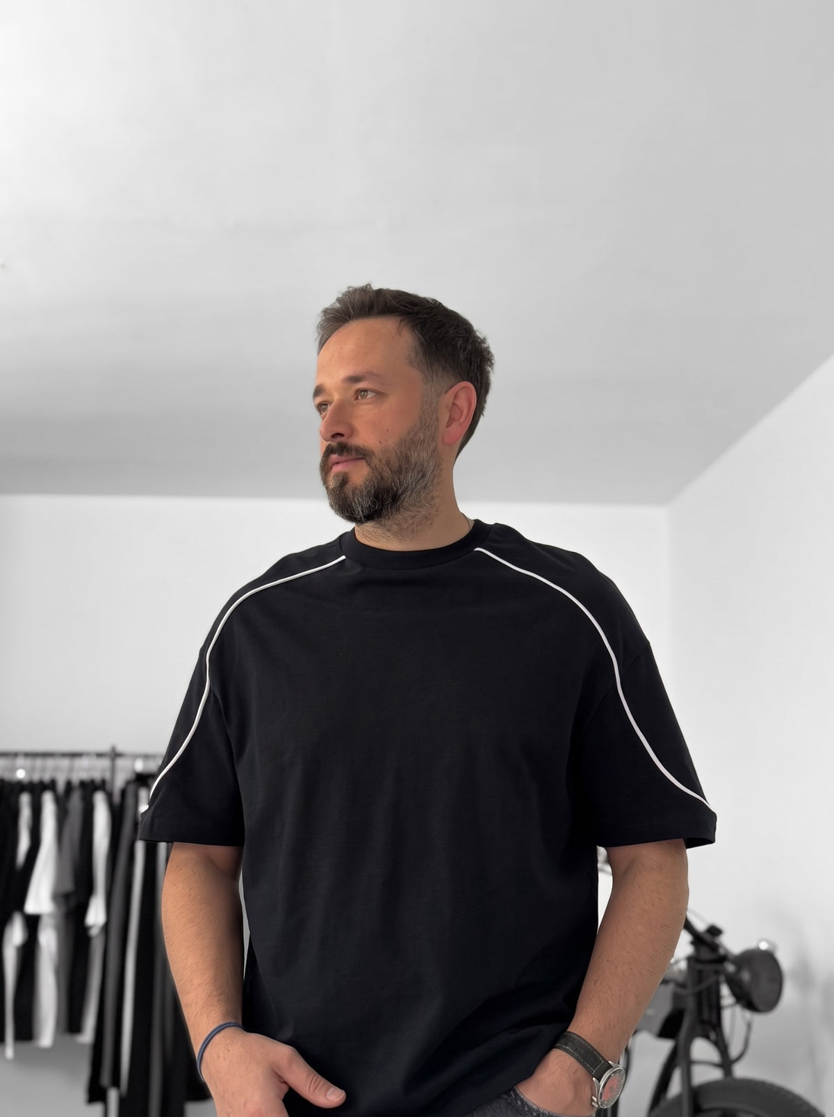 BROEK black piped oversized T-shirt worn with grey jeans, showing the dropped shoulders and relaxed fit.