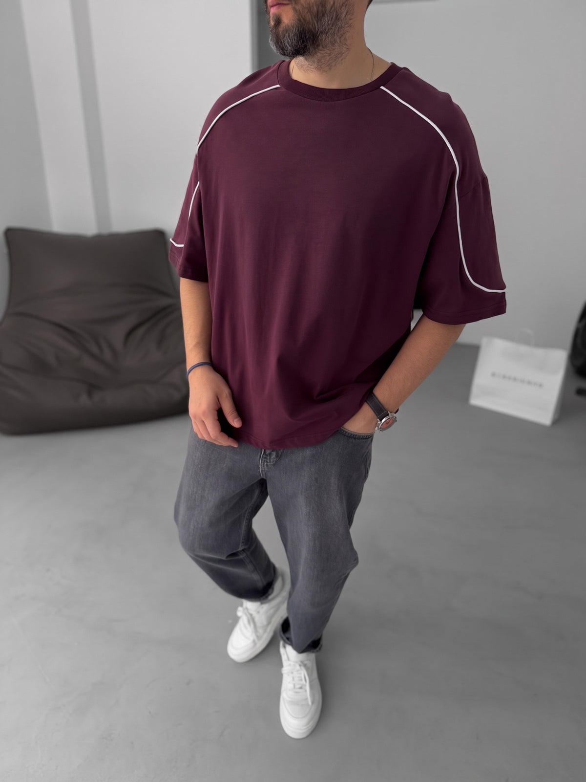 BROEK burgundy piped oversized T-shirt styled with grey jeans and white sneakers.