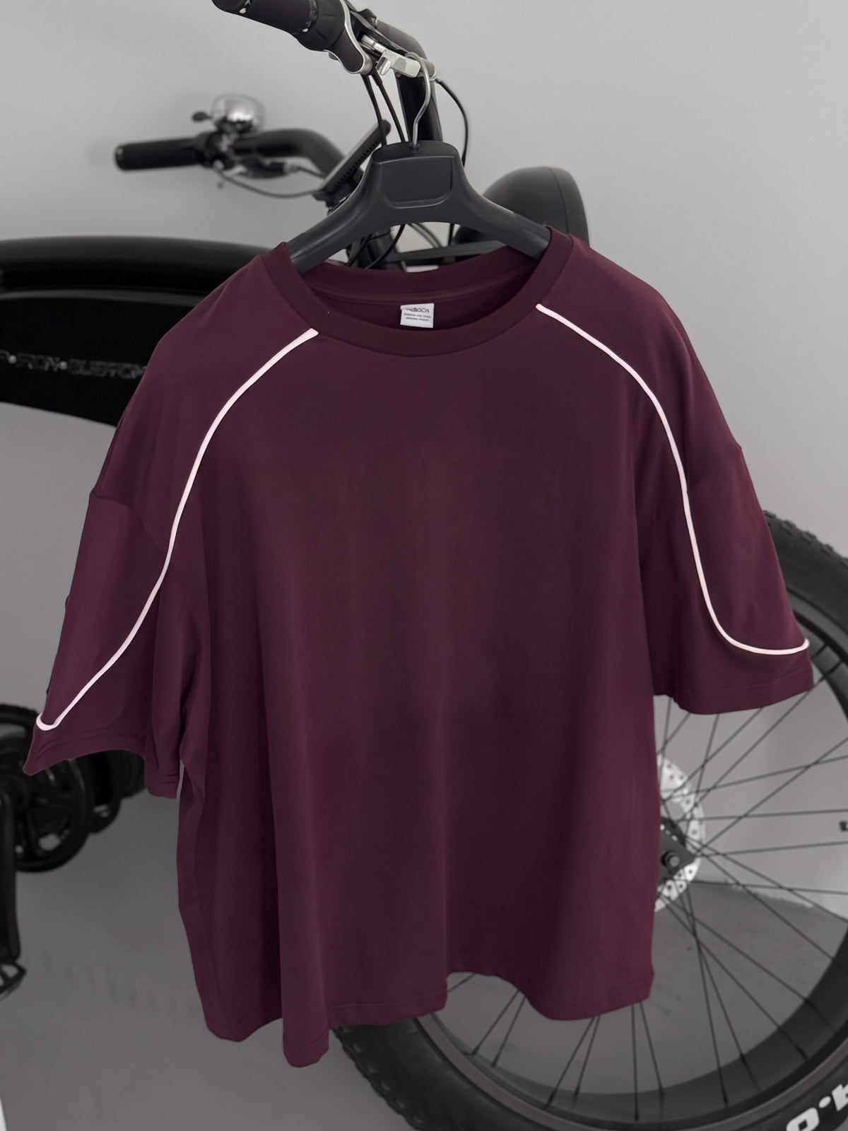 BROEK burgundy oversized crew-neck T-shirt on a hanger, front view with white contrast piping.
