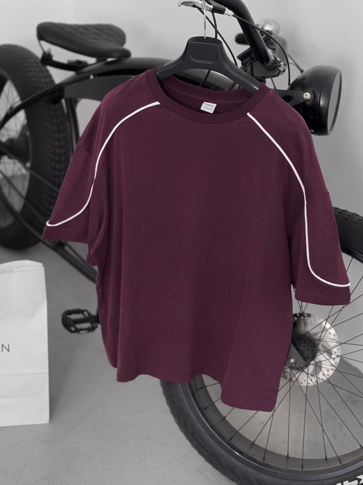 BROEK burgundy piped oversized T-shirt on a hanger, alternate view of the neckline and curved sleeve piping.