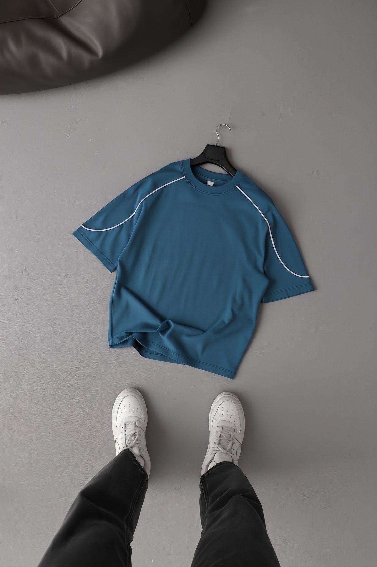 BROEK petrol blue oversized T-shirt on a hanger, showing curved white piping and short sleeves.