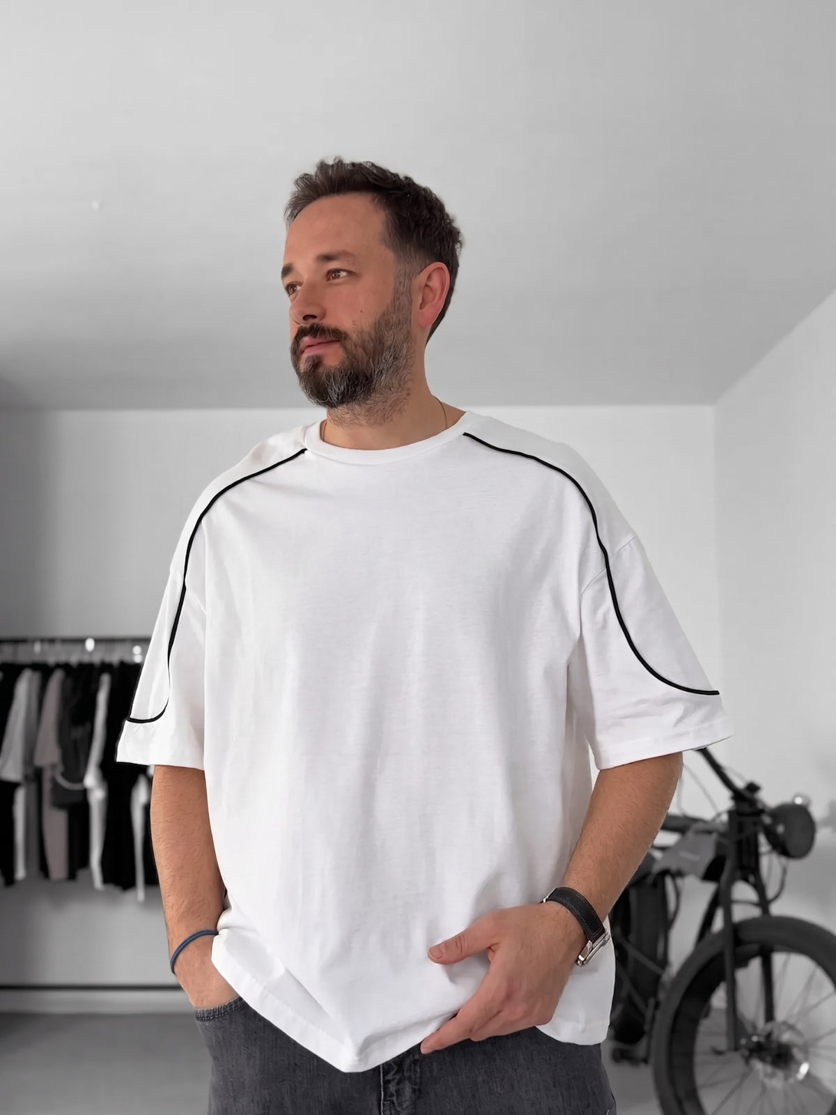 BROEK white piped oversized T-shirt worn with grey jeans, showing the relaxed fit and short sleeves.